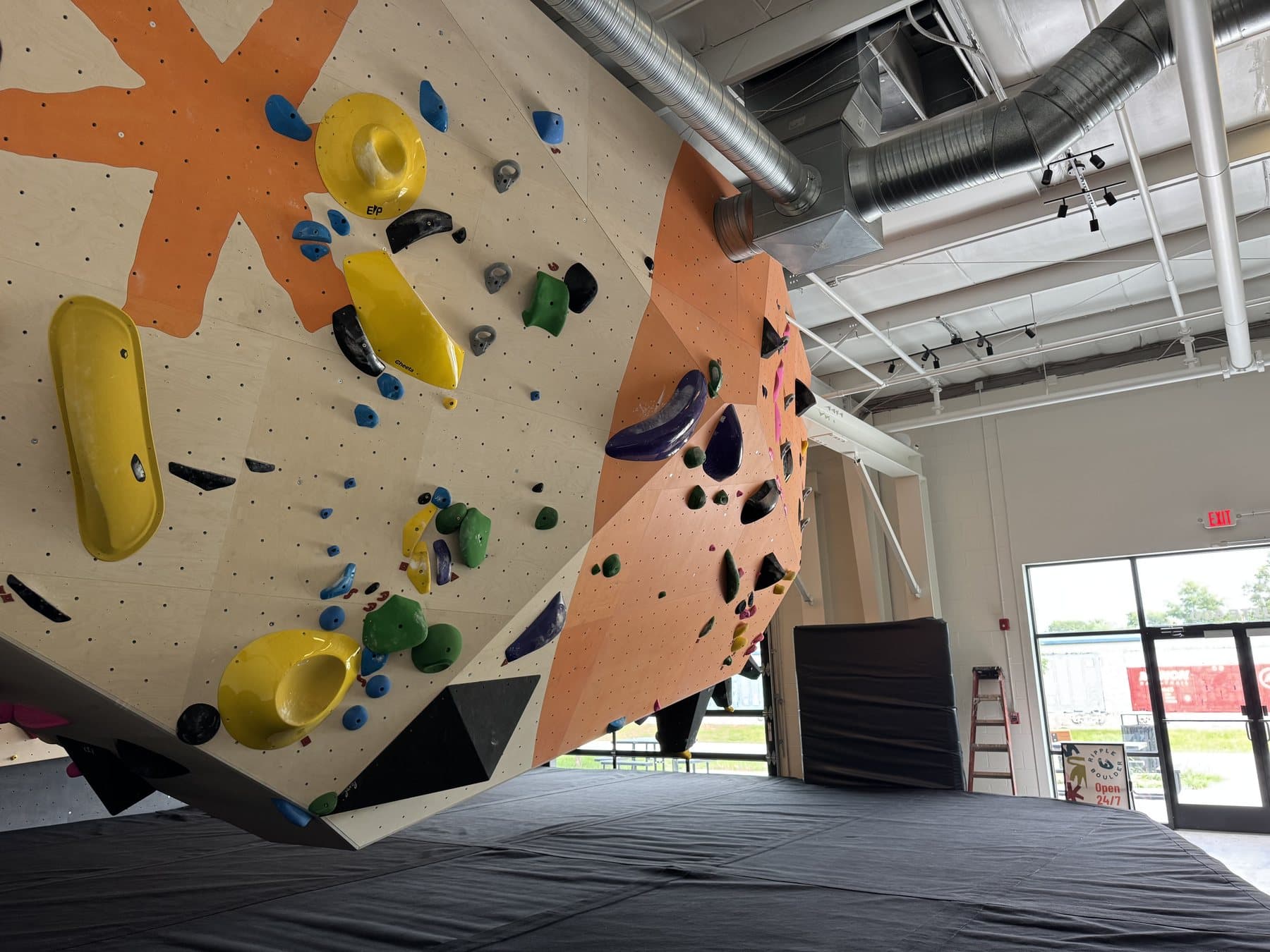 Looking up at Ripple Boulder's floating boulder — the overhanging prow, set with colorful holds